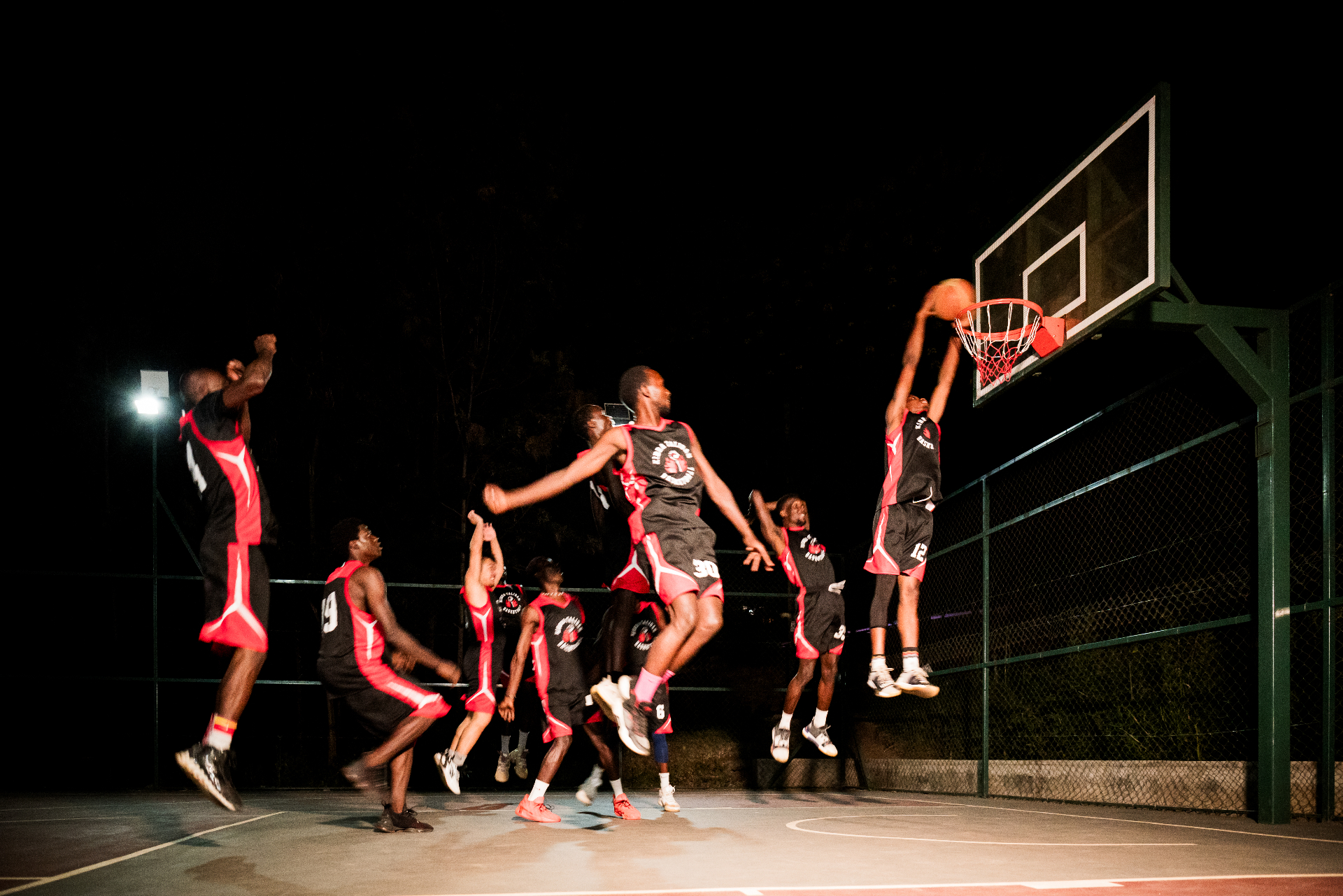 Players in mid-air on a Kibera court at night
